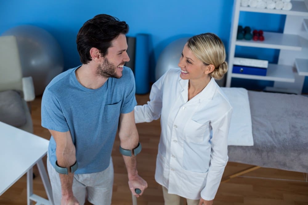 a carer smiling and holding a man with a leg injuiry