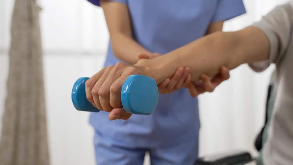 close up shot of a patient's hand holding dumbbell with an exercise physiologist