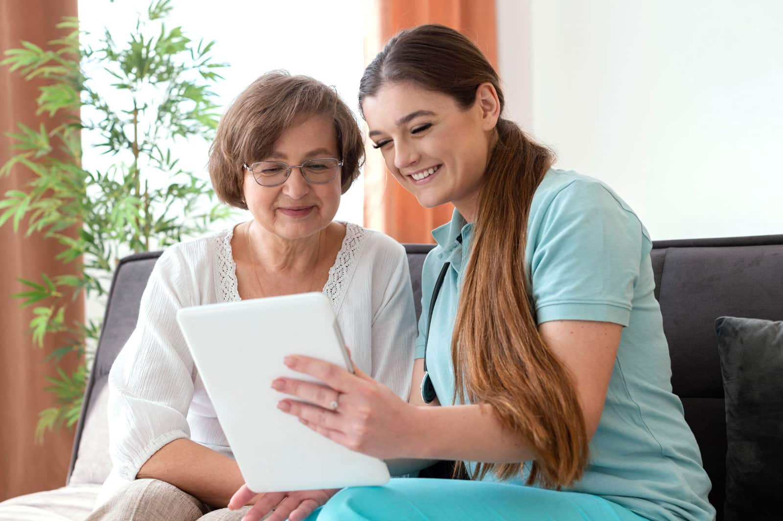 Smiling Nurse with elderly patient looking at iPad. 